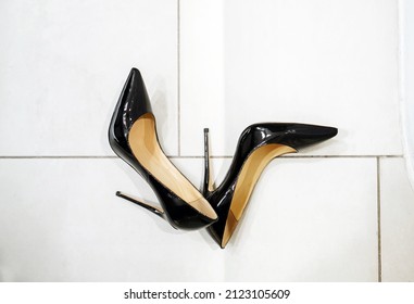 Patent Black Stilettos With A Pointed Toe On A White Tile