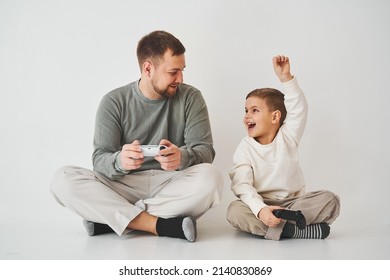 Paternity. Father And Son Play Gamepad Console Game Laugh And Have Fun Together. Gamers Play Computer Games