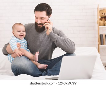 Paternity leave and business. Young dad working on laptop and talking on phone at home while taking care of his baby son, copy space