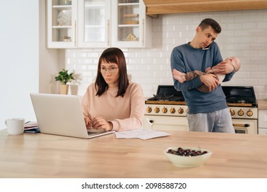 Paternity Leave And Gender Family Roles Concept. Young Business Woman Using Laptop For Remote Work From Home While Her Multitasking Husband Take Care Of Their Toddler Infant Baby And Taking Phone Call