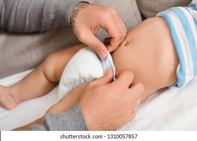 Paternity leave solicitudes. Father changing his baby son diaper, closeup