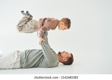 Paternity Lifestyle. Father Lifting Child On White Background. Dad And Child Smile And Having Fun Together