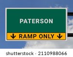 Paterson logo. Paterson lettering on a road sign. Signpost at entrance to Paterson, USA. Green pointer in American style. Road sign in the United States of America. Sky in background