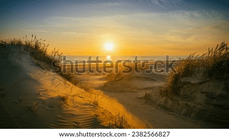 Path between the dunes leads to the beach at sunset
