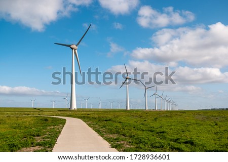 path by the dike to the huge windmill park with huge turbines in the Netherlands Noordoostpolder, green energy wind mill park in Flevoland