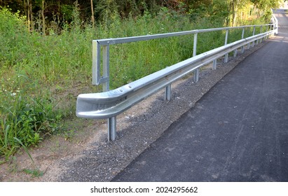 path for cyclists with an asphalt surface. galvanized iron railing over road barriers. Bridge railing with tilting to the sides. railing made of perforated sheet metal in the shape of a triangle