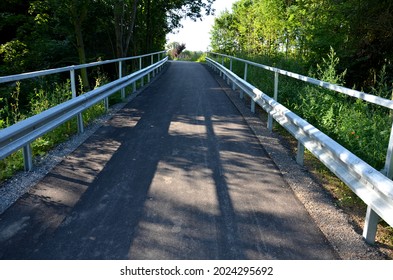 path for cyclists with an asphalt surface. galvanized iron railing over road barriers. Bridge railing with tilting to the sides. railing made of perforated sheet metal in the shape of a triangle