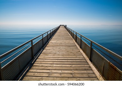 A path to infinity. Long seaside pier reaching the sky. 