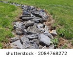 Path of large gray rocks in the middle of field of green grass.