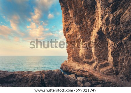 Path leading through the grot at sunset in Crimea. Beautiful landscape with cave, stones, rocks, trail, sea and blue sky with clouds in the evening. Travel and adventure in summer.