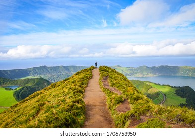 A path leading to viewpoint Miradouro da Boca do Inferno in Sao Miguel Island, Azores, Portugal. Amazing crater lakes surrounded by green fields and forests. Tourist at the end of the scenic way.