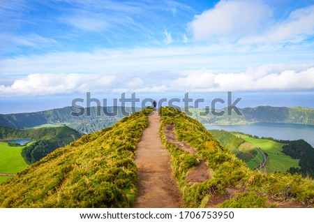 A path leading to viewpoint Miradouro da Boca do Inferno in Sao Miguel Island, Azores, Portugal. Amazing crater lakes surrounded by green fields and forests. Tourist at the end of the scenic way.