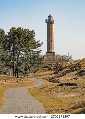 A path leads through the dune landscape to the lighthouse on the island of Norderney, Germany