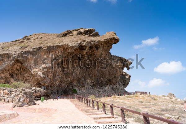 path to the marneef cave and blow holes in\
Salalah Oman, Fantastic seascape, great outdoor scene of Beauty of\
nature concept background,  large ledge, blue sky, few clouds,\
rocks, wooden railing