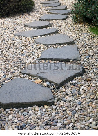 Path of plated stones on gravel bed in Japanese Garden. Meditative stone walkway. Garden architecture, pathway accessory to garden pond.