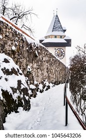 Path to snow covered Uhrturm clocktower landmark of city Graz on hill Schlossberg in winter