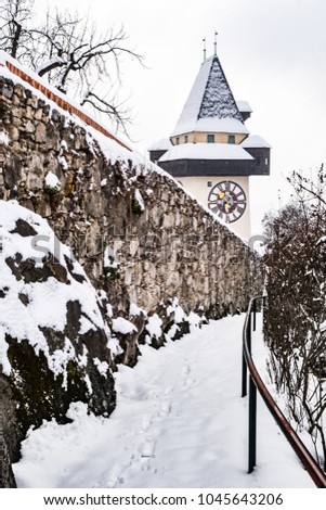 Path to snow covered Uhrturm clocktower landmark of city Graz on hill Schlossberg in winter