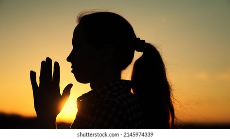 Path of soul to God through prayer. Silhouette Young woman praying at sunset. Christian prayer in nature. Morning prayer of girl outdoors. Freedom of religion. Era of mercy, kindness, love.