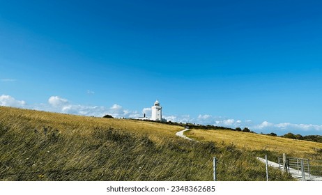 Path to success. Costal Pathway leading to white light house standing at a far stretch. - Powered by Shutterstock
