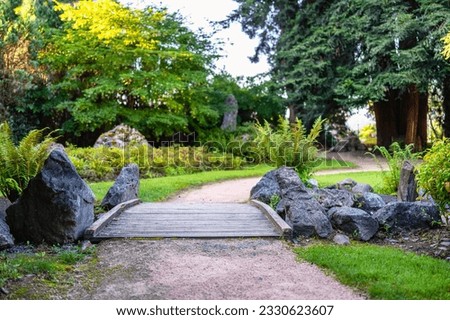 Path that passes through a small wooden bridge in a Japanese-style garden.
