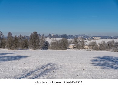A path through the forest around the town of Marianske Lazne by the cemetery in winter in sunny weather with snowy details in the surroundings.