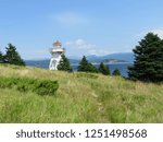 A  path through to the tall grass to a small lighthouse at Woody Point, in Gros Morne National Park, Newfoundland and Labrador, Canada.  It is a beautiful summer day with blue sky.