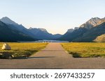 Path to tranquil lake framed by majestic mountains under a clear, blue sky. Waterton, AB