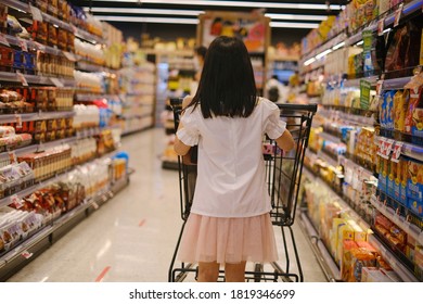 Pathumwan, Bangkok / Thailand - 09/09/2020: The Back View Of A Young Asian Girl Pushing A Shopping Cart Along An Aisle At A A High Class Supermarket On The Top Floor Of Central Word Shopping Center. 