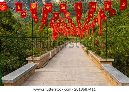Pathway adorned with red flags, featuring Vietnam's star and the hammer and sickle, creating an inviting archway in Huyn Trung Khanh, Vietnam