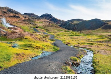 Pathway by stream flowing in mountain. Beautiful view of amidst green moss covered landscape against blue sky. Idyllic picturesque of volcanic valley in Alpine region. - Shutterstock ID 2182095155