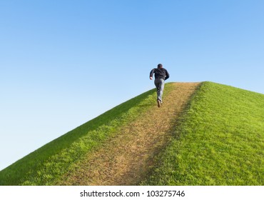 Pathway up the hill against the sky. Man ran to the top. Symbol development or career growth.