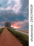 Pathway leading to modern circular building by the beach at sunset with dramatic cloudy sky in Middelkerke, Belgium


