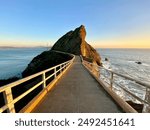 Pathway leading to the Point Bonita rocky outcrop over the ocean during sunset, capturing a scenic and tranquil coastal view