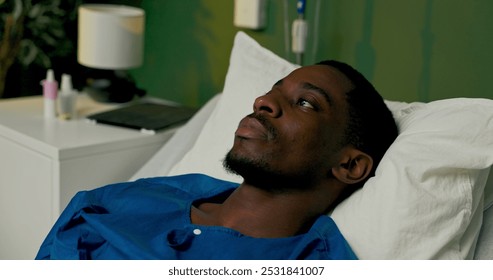 Patient from Africa rests in the hospital bed, calmly gazing forward, taking in the surroundings. - Powered by Shutterstock