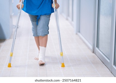 Patient with ankle sprain foot injury wearing a bandage, and using a walking stick to support the weight of the foot. Medical healthcare Physical therapy crutches tools and equipment. - Powered by Shutterstock