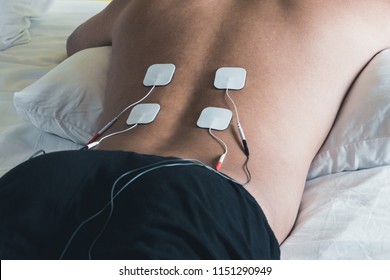 Patient applying electrical stimulation therapy on back. Electrical tens.