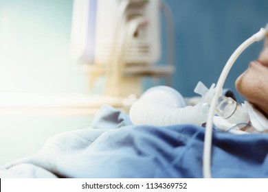 Patient asian elder women 80s do tracheostomy use ventilator for respiration breathing help on patient bed in intensive care unit (ICU.) room at hospital.
