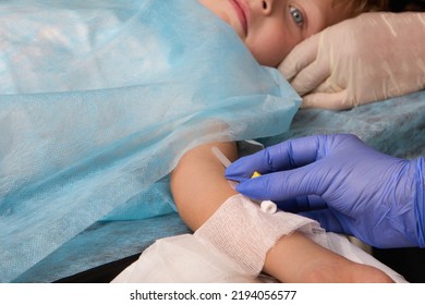 Patient Child Lies On The Operating Table With A Medication Catheter In His Hand. Close-up Of A Butterfly Needle Used To Resuscitate Young Children Is Installed In A Child's Hand