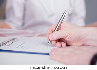 The Patient Completes The Questionnaire In A Doctor's Office. Pen In Hand. The Image Depth Of Field.