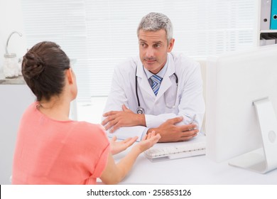 Patient Consulting A Serious Doctor In Medical Office