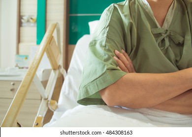 Patient Cross One's Arms On The Hospital Bed. Sick Person Fold One's Arms Over The Chest In Bad Mood.