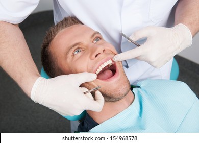 Patient At Dentist Office. Top View Of Man Sitting At The Chair In Dental Office And Keeping Mouth Open