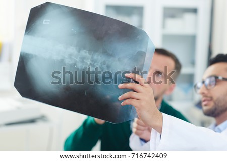 Patient and doctor looking at x-ray image and discussing problem with spinal cord