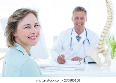 Patient and doctor smiling at camera in medical office - Powered by Shutterstock