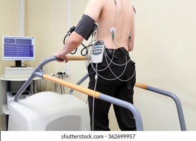 patient with ECG electrodes on back and an instrument for measuring blood pressure during exercise on treadmill