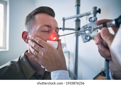 Patient At ENT Clinic. Specialist Doctor - Otolaryngologist Doing Nose Examination Of Young Man.