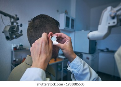 Patient At ENT Clinic. Specialist Doctor - Otolaryngologist Doing Ear Examination Of Young Man.