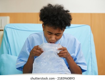 Patient Feeling Stressed And Vomiting Into Plastic Bag On Bed In Hospital