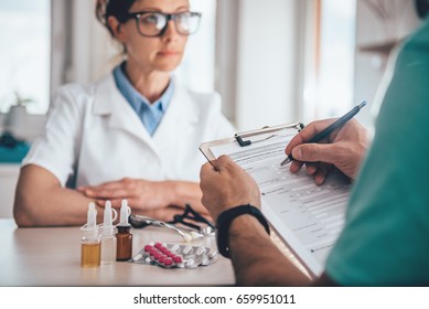 Patient Filing Health Insurance Claim Form In The Doctors Office