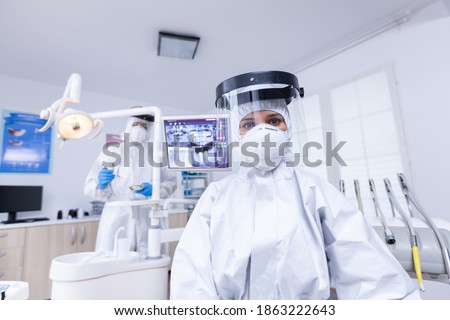 Patient first person view of dentist looking down in covid hazmat suit treating teeth. Stomatolog wearing safety gear against coronavirus during heatlhcare check of patient. [[stock_photo]] © 